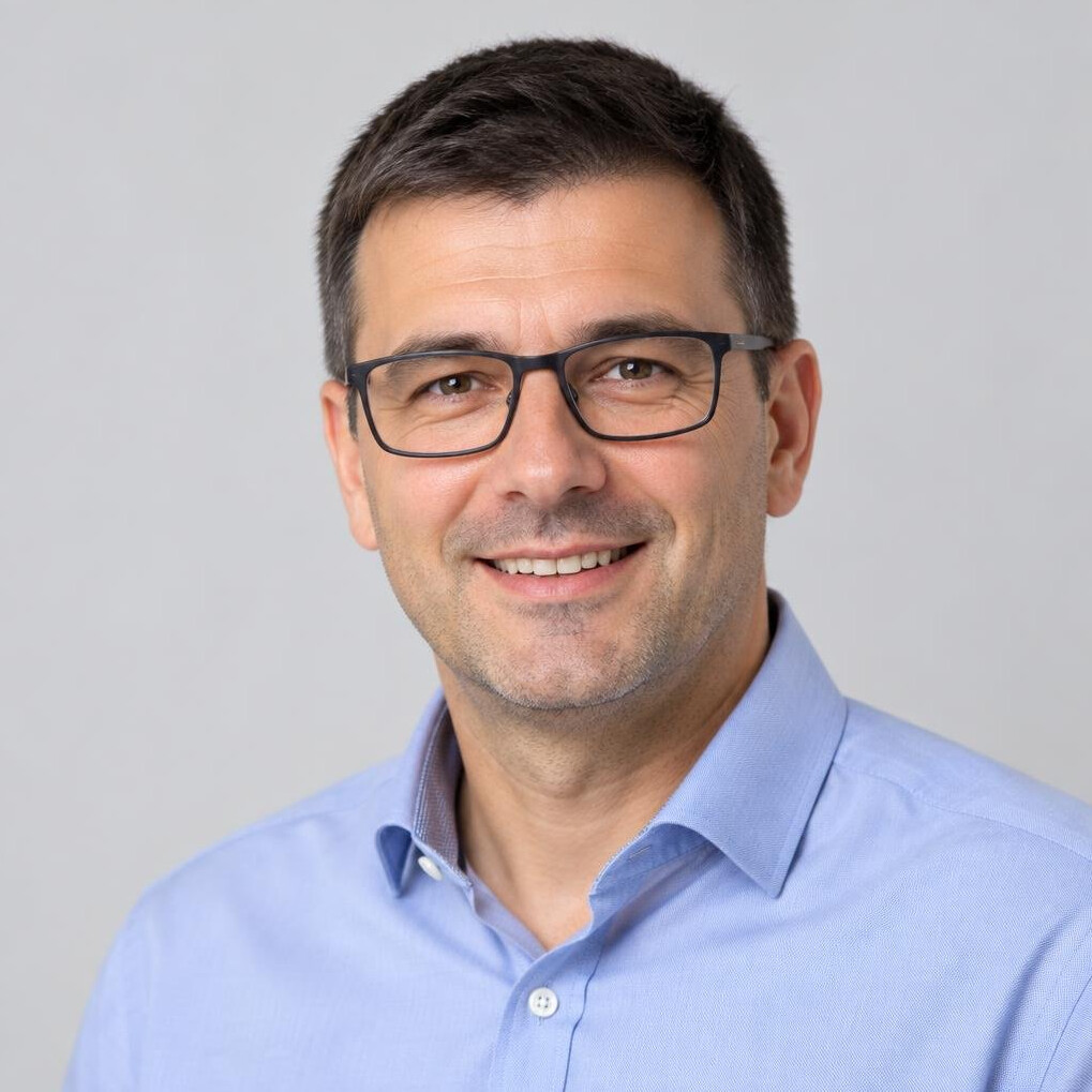 Studio portrait of a smiling Croatian man with short dark hair and glasses